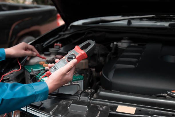Mechanic uses multimeter to check car battery