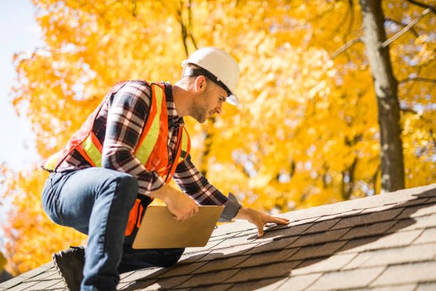 A man with hard hat standing on steps inspecting house roof