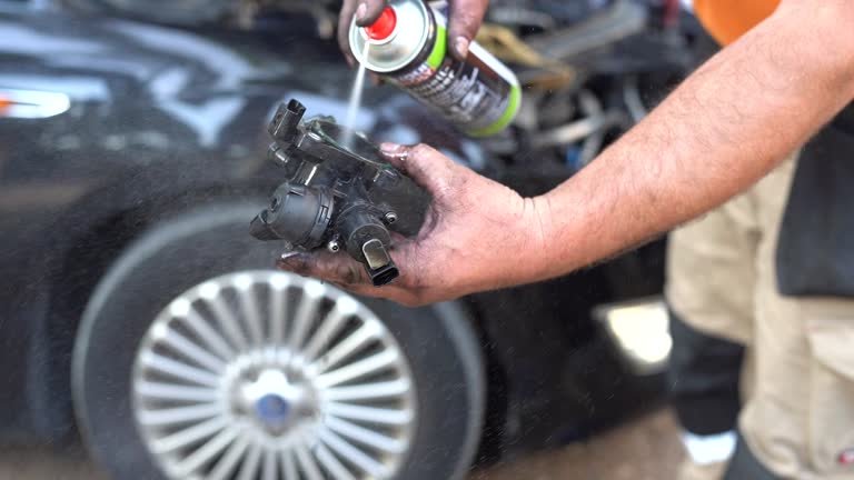 Mechanic Cleaning a Car Part with Spray Degreaser
